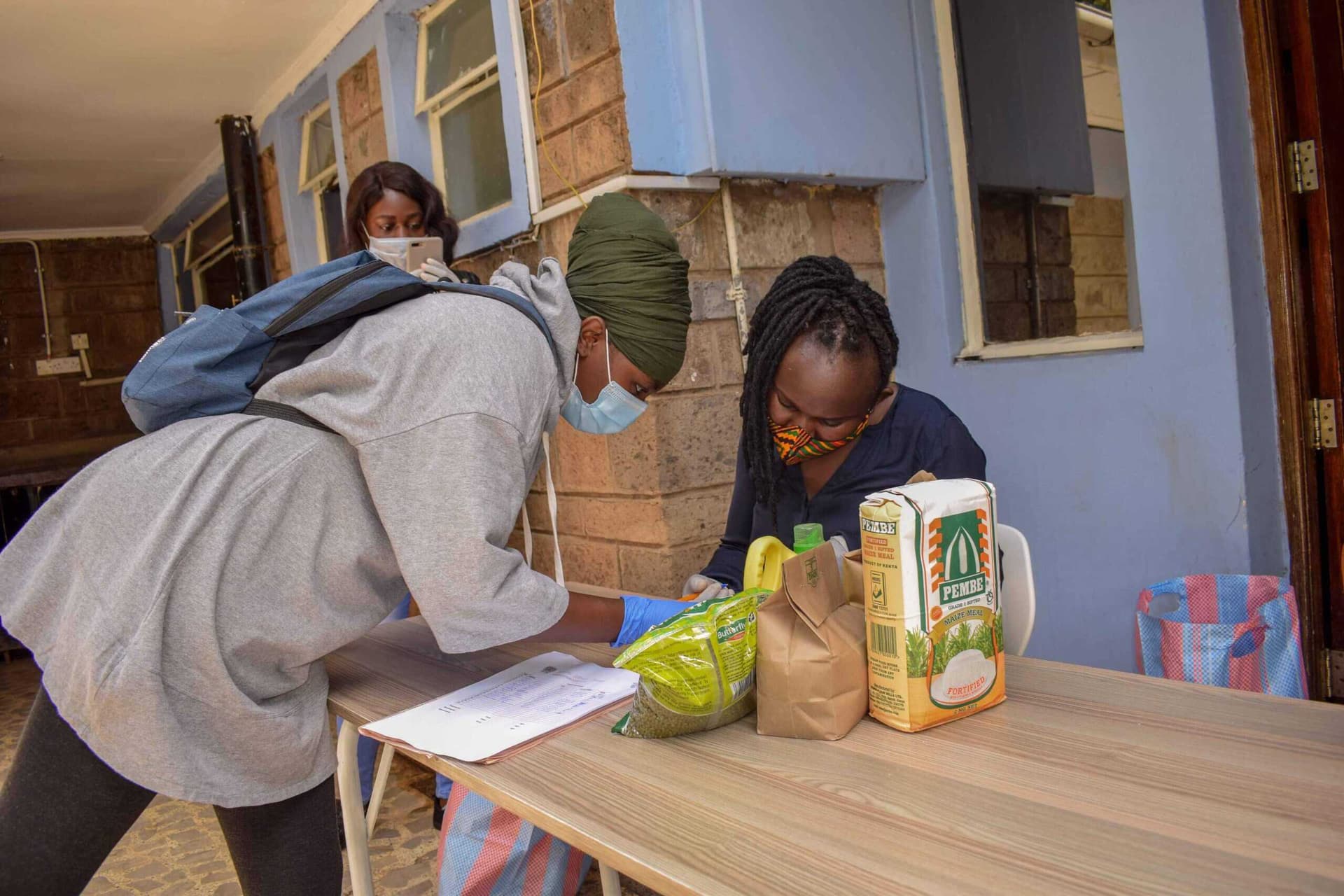 A young person signing for a food package handed out by NairoBits staff